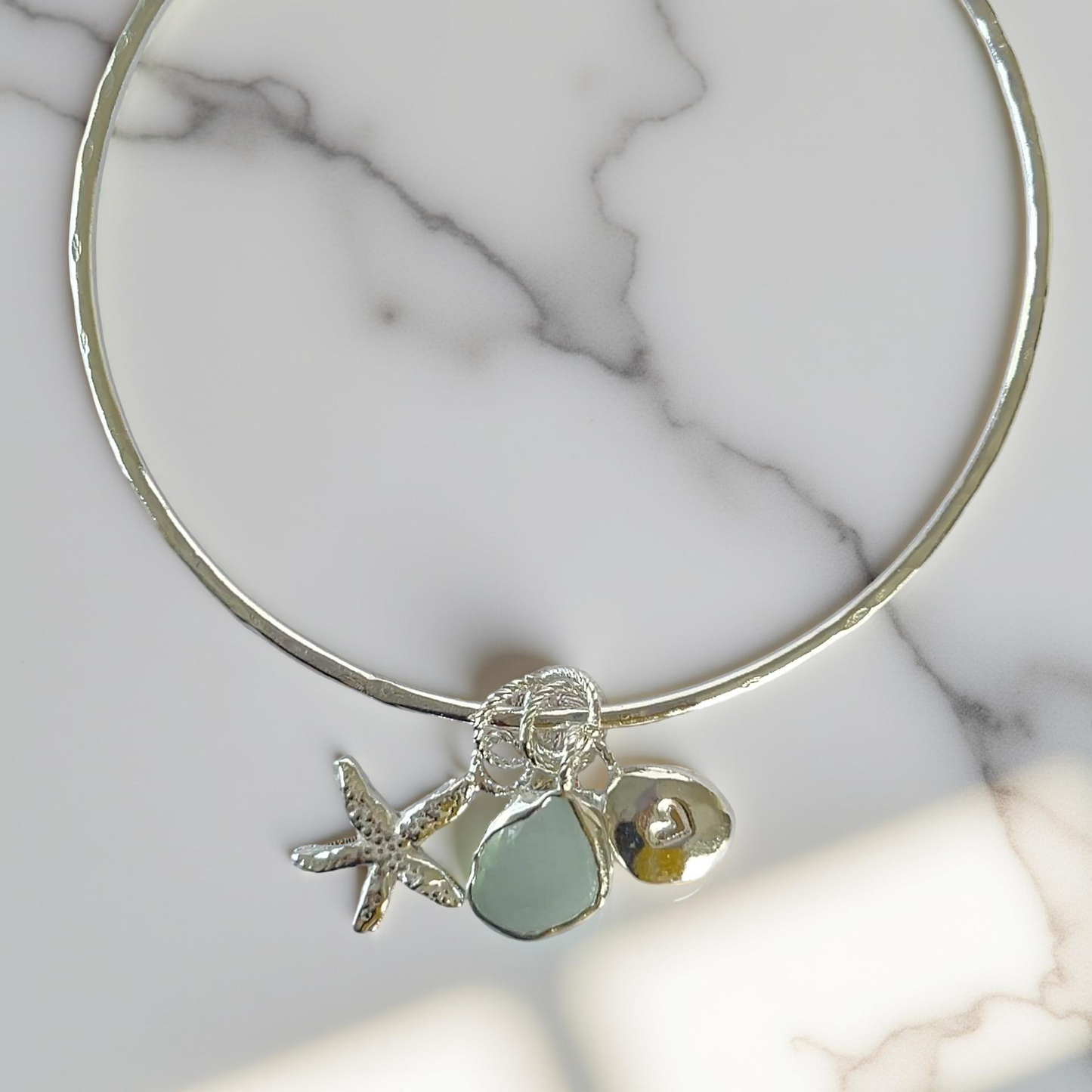 Silver bracelet with starfish and sea glass charm on a wooden surface - SilverLines Jewellery