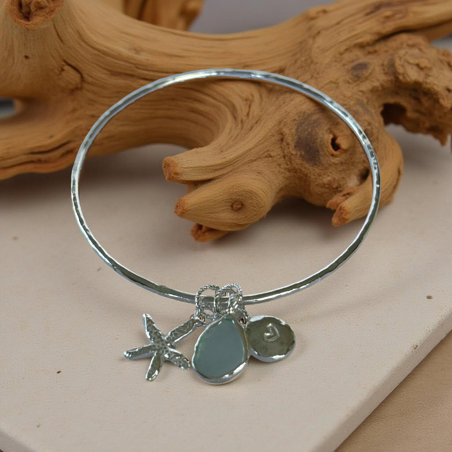 Silver bracelet with starfish and sea glass charm on a wooden surface - SilverLines Jewellery