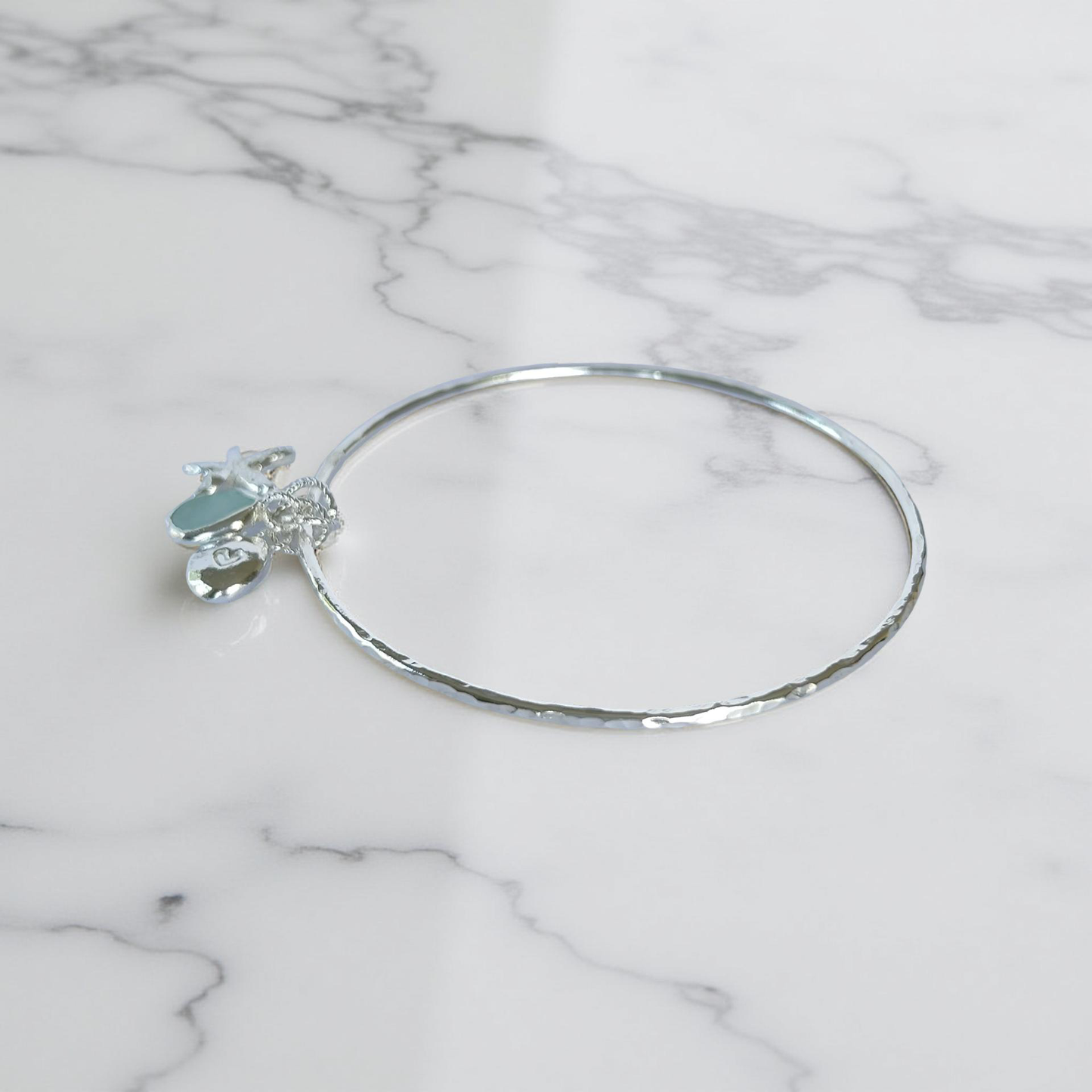 Silver bracelet with starfish and sea glass charm on a wooden surface - SilverLines Jewellery