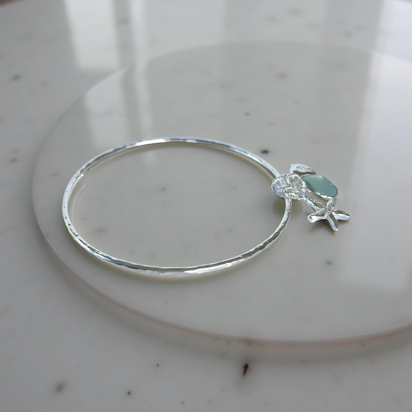 Silver bracelet with starfish and sea glass charm on a wooden surface - SilverLines Jewellery
