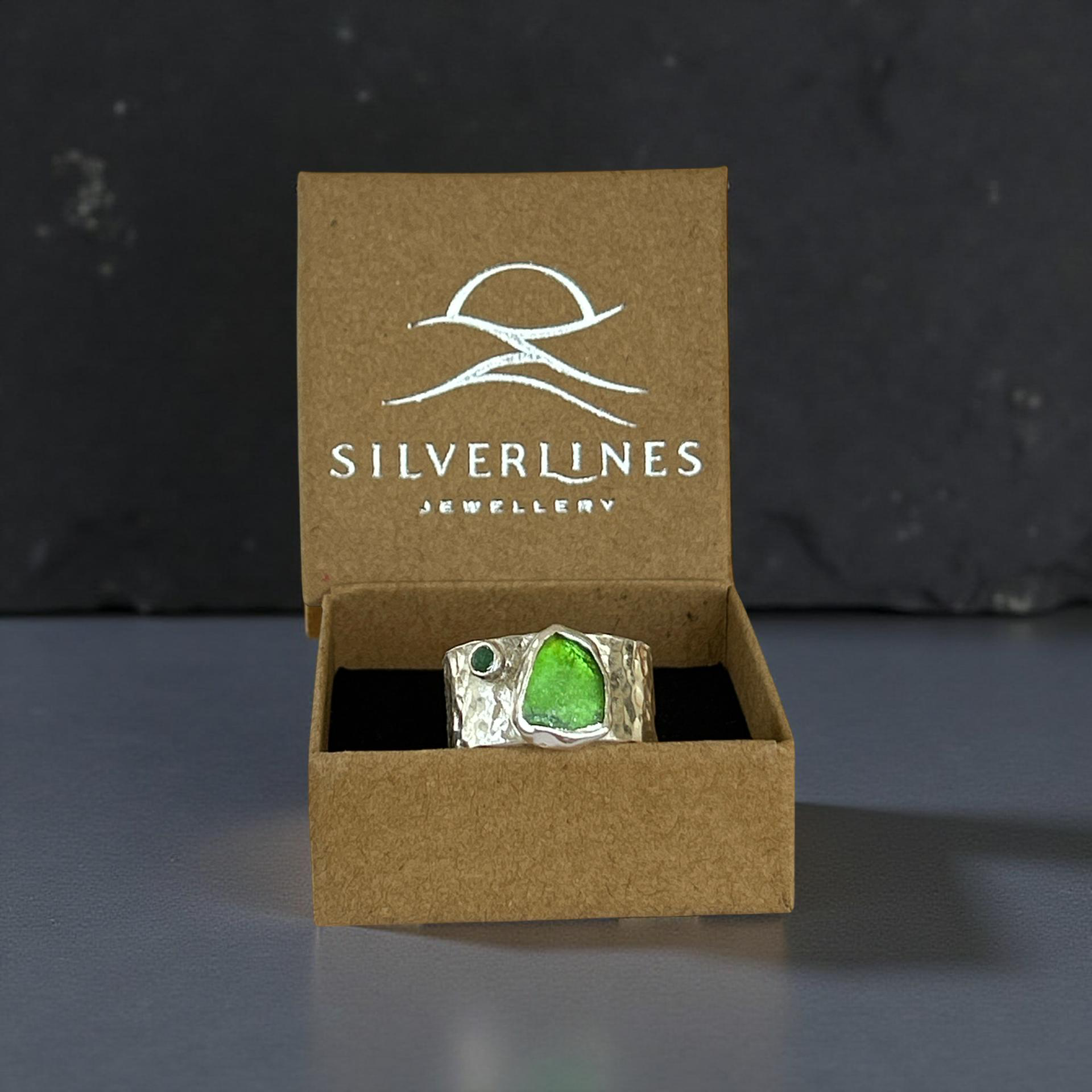 Green gemstone ring in a 'Silverlines Jewellery' box on a dark background