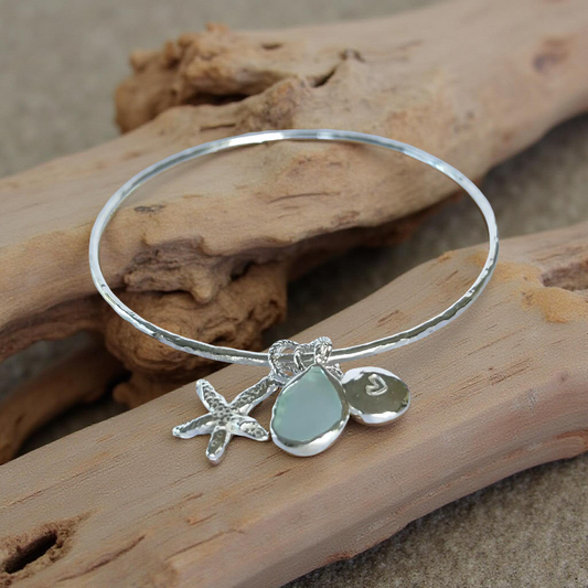 Silver bracelet with starfish and sea glass charm on a wooden surface - SilverLines Jewellery