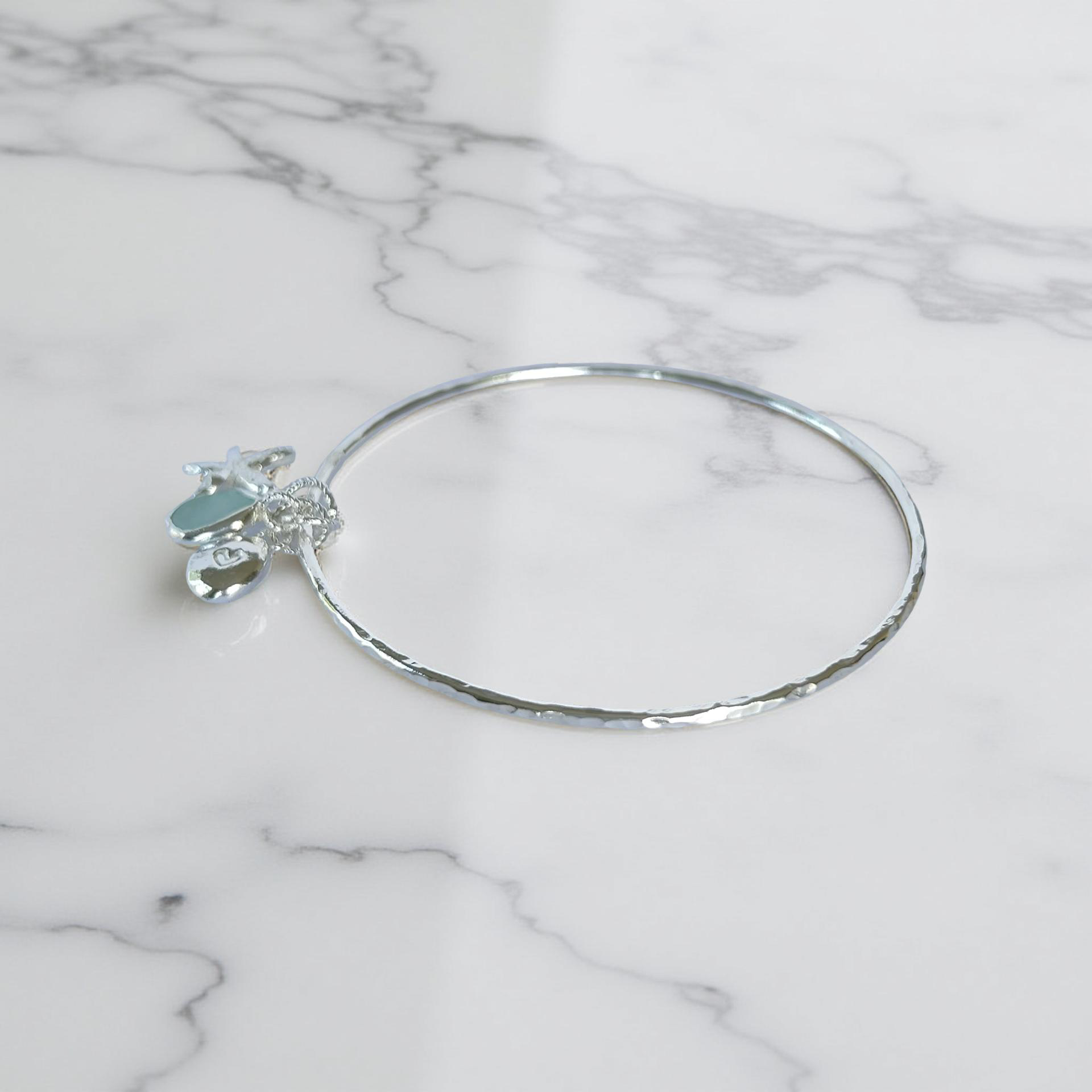 Silver bracelet with starfish and sea glass charm on a wooden surface - SilverLines Jewellery