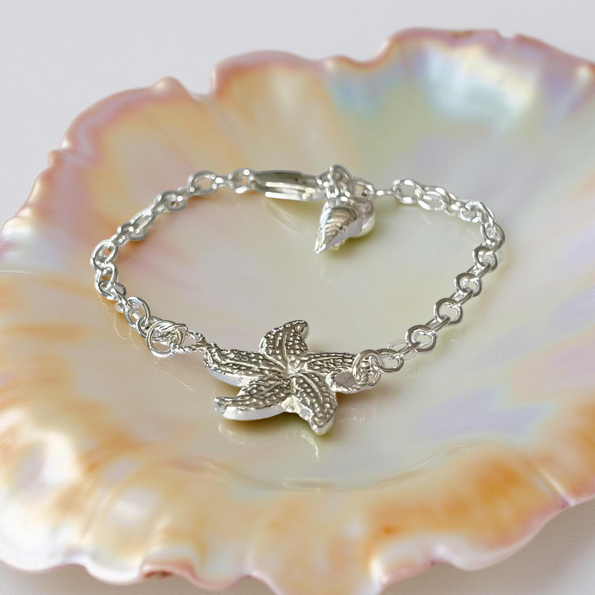 Silver bracelet with a starfish charm on a seashell