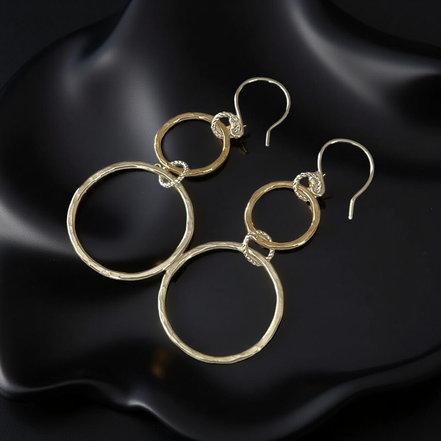 Gold hoop earrings on a black satin background