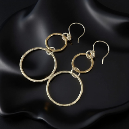 Gold hoop earrings on a black satin background