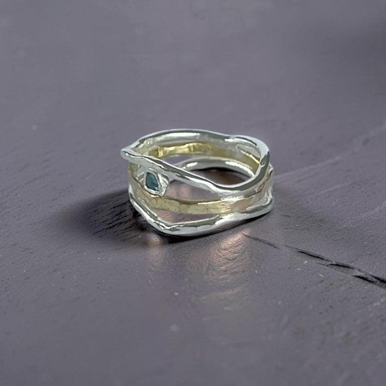 Silver ring with a green gemstone on a dark gray surface