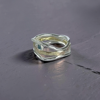 Silver ring with a green gemstone on a dark gray surface