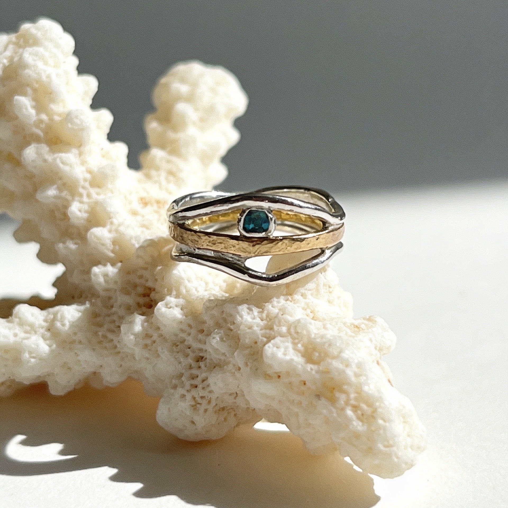 Gold ring with a green gemstone on a piece of coral
