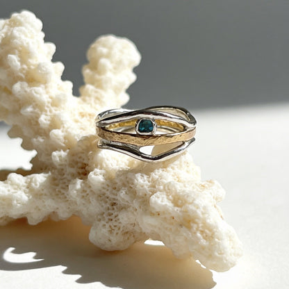 Gold ring with a green gemstone on a piece of coral