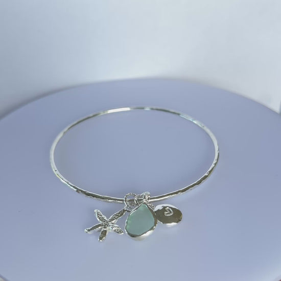 Silver bracelet with starfish and sea glass charm on a wooden surface - SilverLines Jewellery