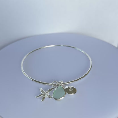 Silver bracelet with starfish and sea glass charm on a wooden surface - SilverLines Jewellery